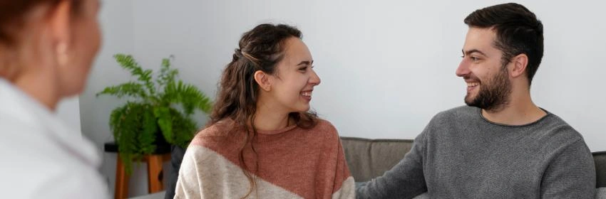 casal sorrindo com psicologa com prancheta na mão